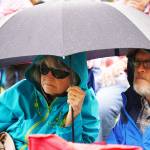 Attendees huddle under umbrellas and in raincoats during the Levitt AMP Soldotna Music Series on Wednesday, June 7, 2023, at Soldotna Creek Park in Soldotna, Alaska. (Jake Dye/Peninsula Clarion)