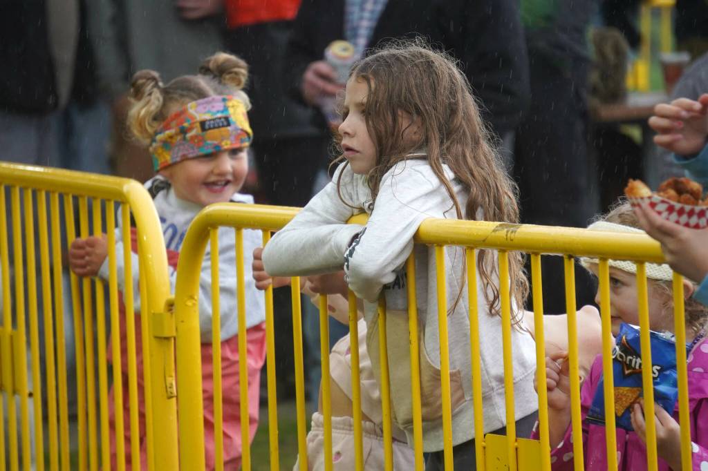 Children listen to Hope Social Club under rainfall during the opening night of the 2024 Levitt AMP Soldotna Music Series at Soldotna Creek Park in Soldotna, Alaska, on Wednesday, June 5, 2024. (Jake Dye/Peninsula Clarion)