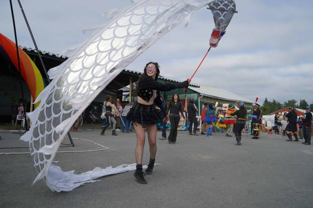 A performer dances with a long dragon flag at Salmonfest in Ninilchik, Alaska, on Saturday, Aug. 3, 2024. (Jake Dye/Peninsula Clarion)