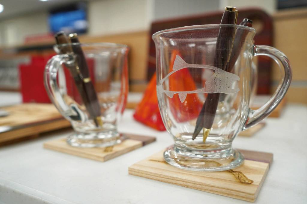 Pens, coasters and engraved glasses crafted by Nikiski Middle/High School students are displayed during a meeting of the Kenai Peninsula Borough School Districts Board of Education in Soldotna, Alaska, on Monday, Feb. 3, 2025. (Jake Dye/Peninsula Clarion)