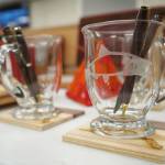 Pens, coasters and engraved glasses crafted by Nikiski Middle/High School students are displayed during a meeting of the Kenai Peninsula Borough School Districts Board of Education in Soldotna, Alaska, on Monday, Feb. 3, 2025. (Jake Dye/Peninsula Clarion)