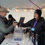 Brewers from Turnagain Brewery hand a freshly filled cup to an attendee at the 10th Annual Frozen River Fest in Soldotna, Alaska, on Saturday, Feb. 15, 2025. (Jake Dye/Peninsula Clarion)