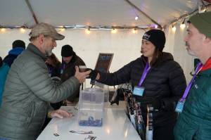 Brewers from Turnagain Brewery hand a freshly filled cup to an attendee at the 10th Annual Frozen River Fest in Soldotna, Alaska, on Saturday, Feb. 15, 2025. (Jake Dye/Peninsula Clarion)
