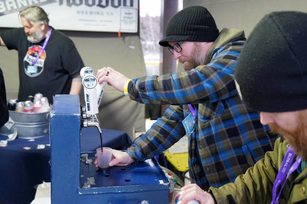 A brewer from Kenai River Brewing Company fills a cup for an attendee at the 10th Annual Frozen River Fest in Soldotna, Alaska, on Saturday, Feb. 15, 2025. (Jake Dye/Peninsula Clarion)