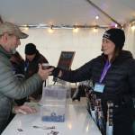 Brewers from Turnagain Brewery hand a freshly filled cup to an attendee at the 10th Annual Frozen River Fest in Soldotna, Alaska, on Saturday, Feb. 15, 2025. (Jake Dye/Peninsula Clarion)