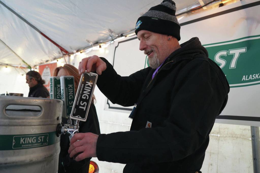 A brewer from King Street Brewing Company pours a cup for an attendee at the 10th Annual Frozen River Fest in Soldotna, Alaska, on Saturday, Feb. 15, 2025. (Jake Dye/Peninsula Clarion)