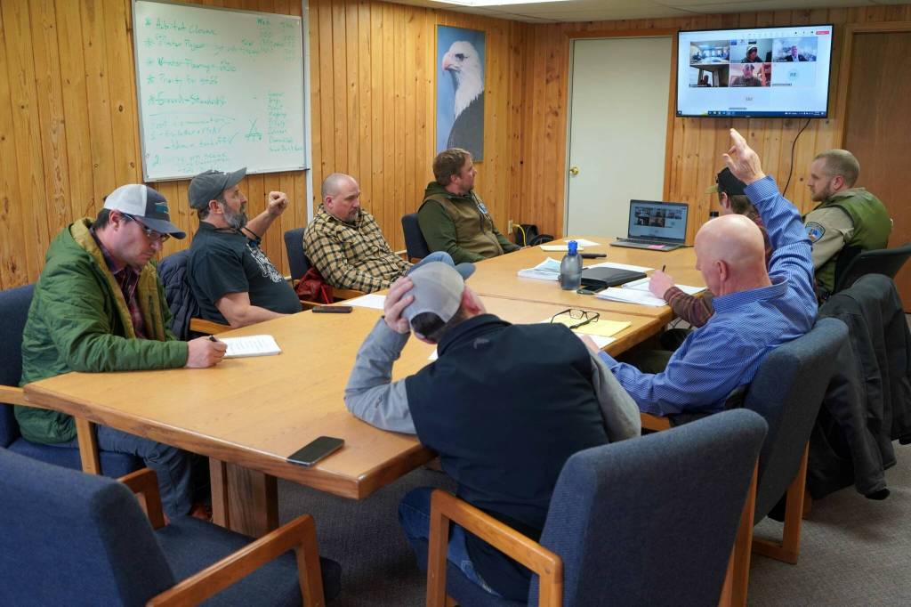 Monte Roberts, left, and Greg Brush, right, raise their hands during an emergency meeting of the Kenai River Special Management Area Advisory Boards guide committee at the Kenai Peninsula Region Office of Alaska State Parks near Soldotna, Alaska, on Feb. 25, 2025. (Jake Dye/Peninsula Clarion)