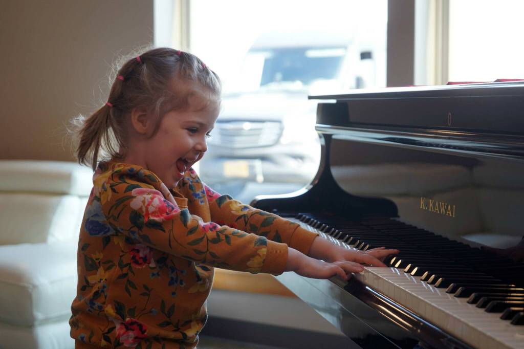 A young girl plays the lobby piano during the opening of the new Triumvirate Theatre in Kenai, Alaska, on Saturday, April 19, 2025. (Jake Dye/Peninsula Clarion)