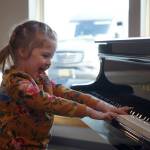 A young girl plays the lobby piano during the opening of the new Triumvirate Theatre in Kenai, Alaska, on Saturday, April 19, 2025. (Jake Dye/Peninsula Clarion)