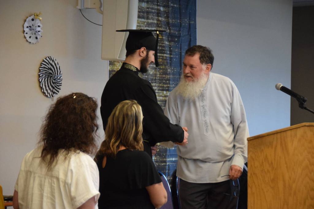 Fiofan Chernishoff (center) shakes Voznesenka School principal Michael Wojciaks hand as he is presented with his diploma during the commencement ceremony held Monday, May 19, 2025, at Lands End Resort in Homer, Alaska. (Delcenia Cosman/Homer News)