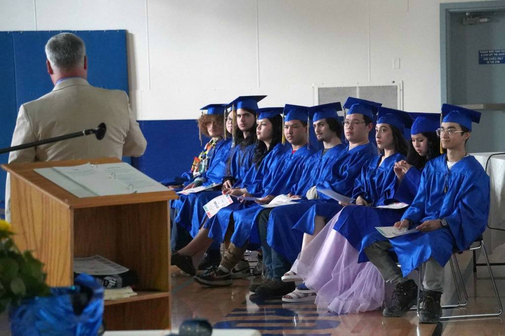 Kenai Alternative High School graduates listen to a speech by Principal John Galahan during their commencement ceremony in the schools gym in Kenai, Alaska, on Wednesday, May 22, 2025. (Jake Dye/Peninsula Clarion)