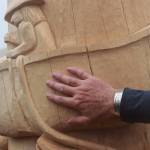 Lead carver Gordon Greenwald touches a carved Tlingit fisherman trolling in a canoe with what he called an old-fashioned lure. (Jasz Garrett / Juneau Empire)