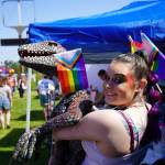 Nala Johnson hoists a velociraptor carrying a progress flag during the Saturday Market at the Goods in Soldotna, Saturday, June 14. (Jake Dye/Peninsula Clarion)