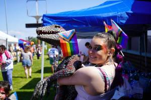 Nala Johnson hoists a velociraptor carrying a progress flag during the Saturday Market at the Goods in Soldotna, Alaska, on Saturday, June 14, 2025. (Jake Dye/Peninsula Clarion)