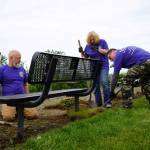 Volunteers clean around benches at Erik Hansen Scout Park in Kenai, Alaska, on Wednesday, June 25, 2025. (Jake Dye/Peninsula Clarion)