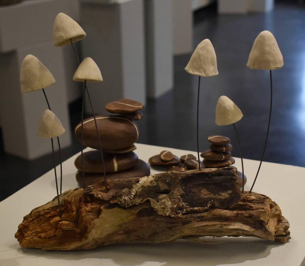 Clay mushrooms sit on a log at the Kenai Potters Guild exhibit, River, hosted by the Kenai Art Center. (Jonas Oyoumick/Peninsula Clarion)