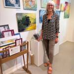 Artist Ingrid McKinstry stands next to her current mixed media exhibit and her work available year-round at Fireweed Gallery in Homer, Alaska. Photo provided by Ingrid McKinstry