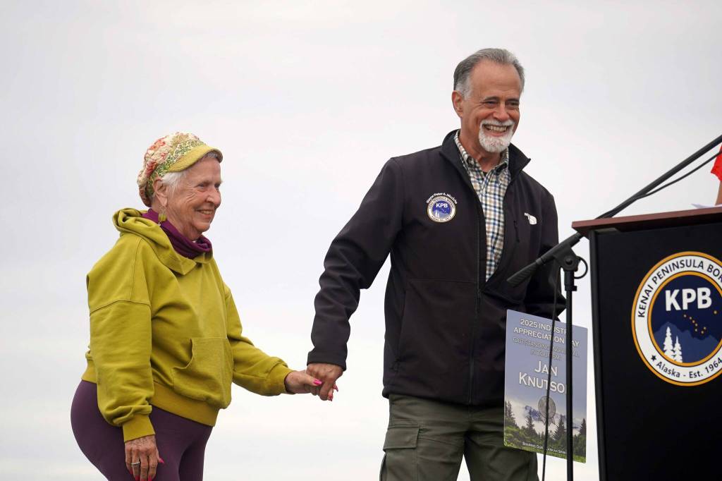 Jan Knutson is accompanied to the podium by Kenai Peninsula Borough Mayor Peter Micciche after winning the Outstanding Individual in Tourism Award during the 2025 Industry Appreciation Day at the Kenai Softball Greenstrip in Kenai, Alaska, on Saturday, Aug. 23, 2025. (Jake Dye/Peninsula Clarion)