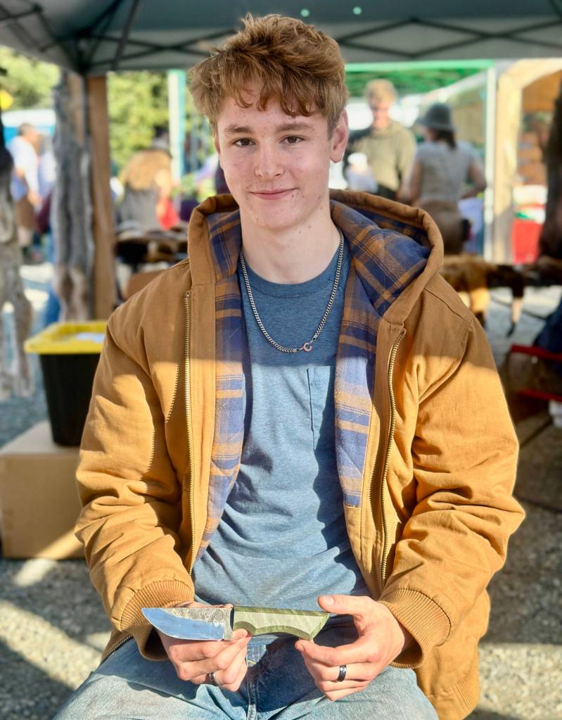 Jaxon Bourne holds one of his handmade knives at the Homer Farmers Market on Saturday, Sept. 13, 2025, in Homer, Alaska. Photo by Christina Whiting