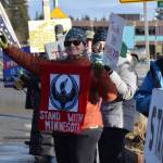 Jan Krehel waves at cars passing by as she holds a Stand With Minnesota banner during the ICE OUT demonstration on Sunday, Feb. 1, 2026, at WKFL Park in Homer, Alaska. (Delcenia Cosman/Homer News)