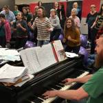 Simon Nissen, Kenai Central choir teacher and founder of the Kenai Peninsula Singers, warms up the singers at Kenai Central before a Monday rehearsal for the Evening of Christmas show. (Photo by Jeff Helminiak/Peninsula Clarion)